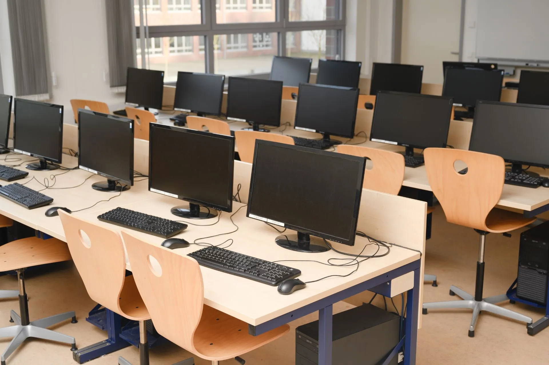 Computer lab with multiple desktop computers arranged neatly on desks, illustrating the characteristics of computers such as speed, accuracy, and versatility.